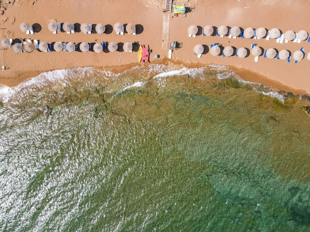 Veduta aerea dall'alto della spiaggia con file di ombrelloni e mare trasparente