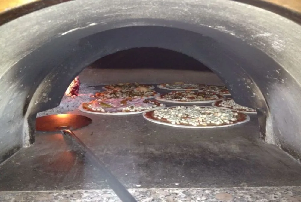 Pizze in cottura all'interno di un forno a legna tradizionale