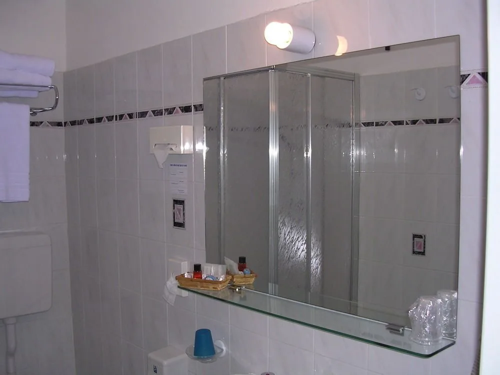 Bagno piastrellato con grande specchio, doccia e set di cortesia