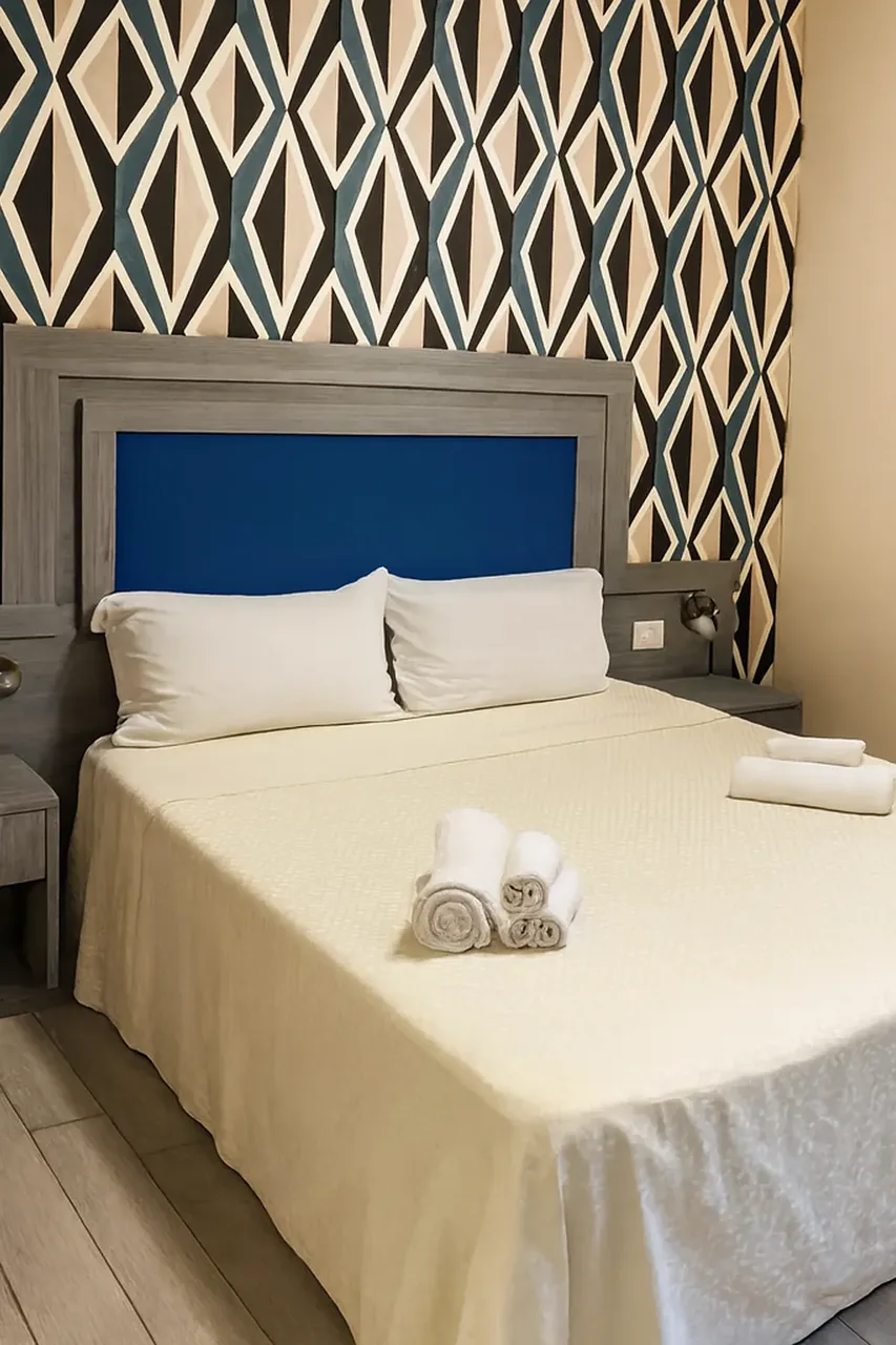 Camera da letto con letto matrimoniale, testiera blu e parete decorata a rombi