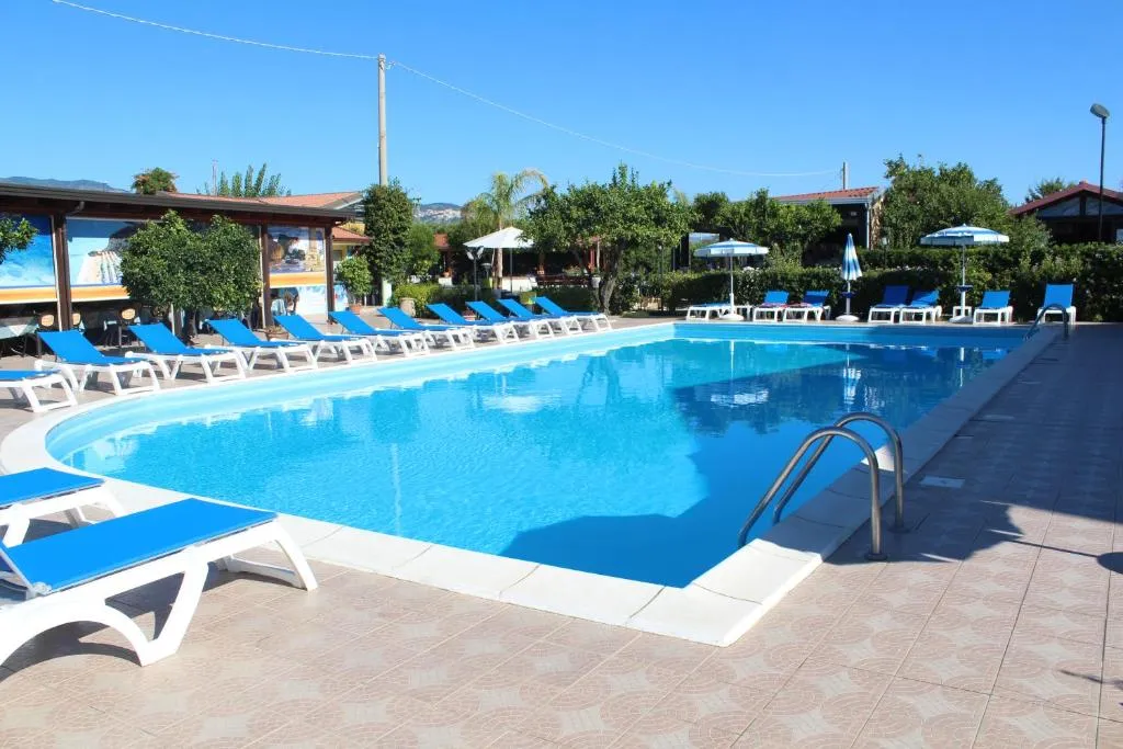Piscina con acqua azzurra, lettini blu e bianchi e ombrelloni
