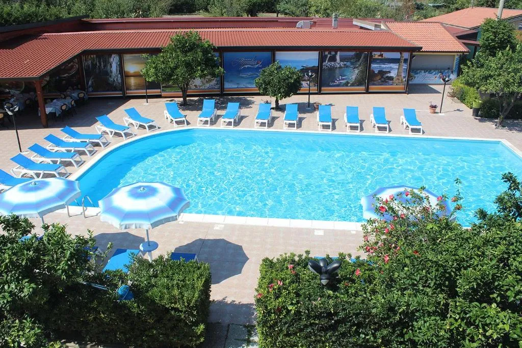 Piscina circondata da lettini blu, ombrelloni e vegetazione