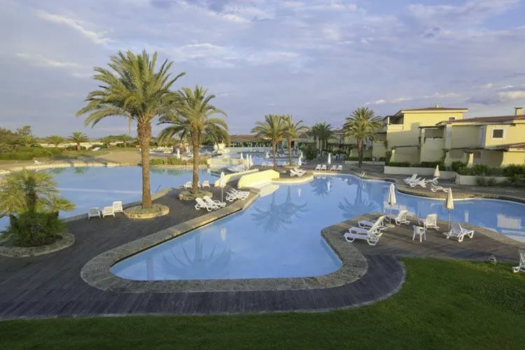 Piscina a forma di laguna con palme e lettini al tramonto