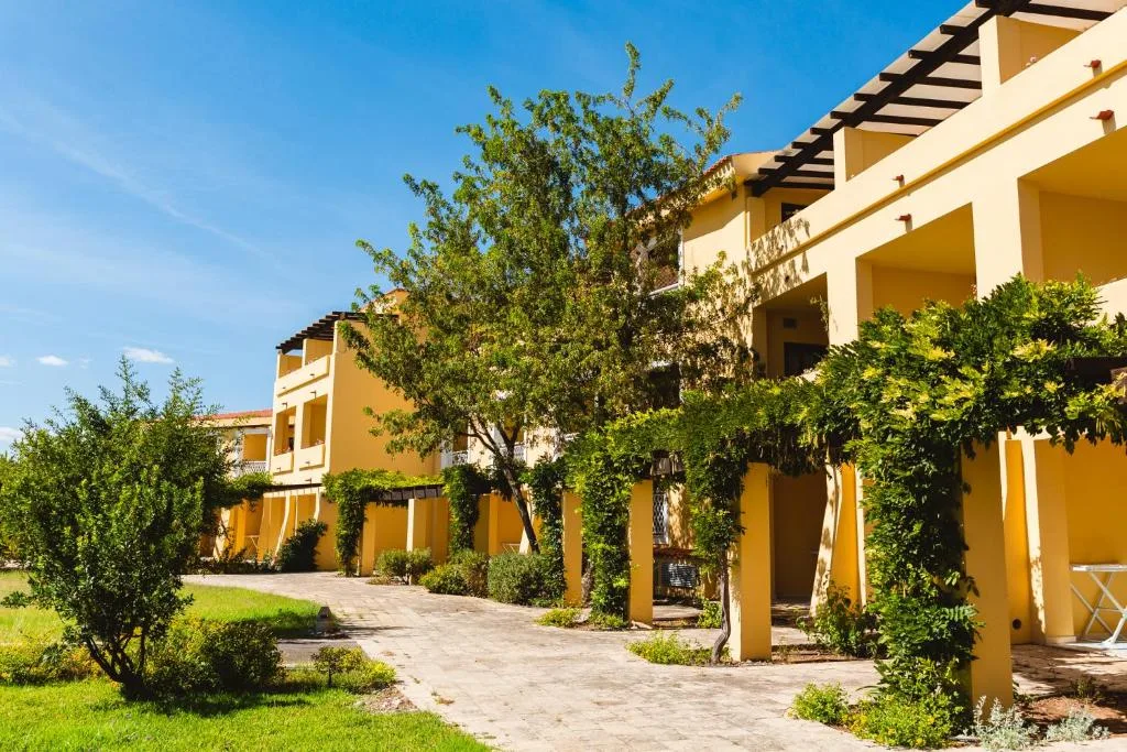 Esterno di edifici gialli con pergolati, verde rampicante e giardino