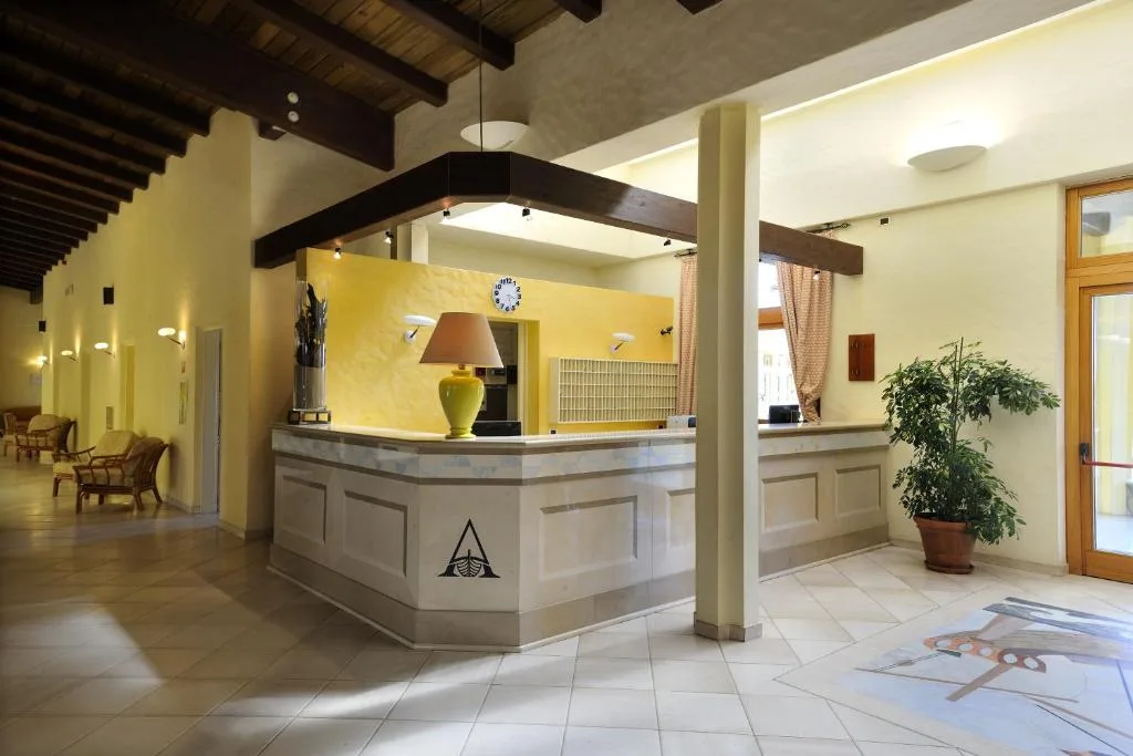 Reception dell'hotel con banco in muratura, travi in legno e ambiente luminoso