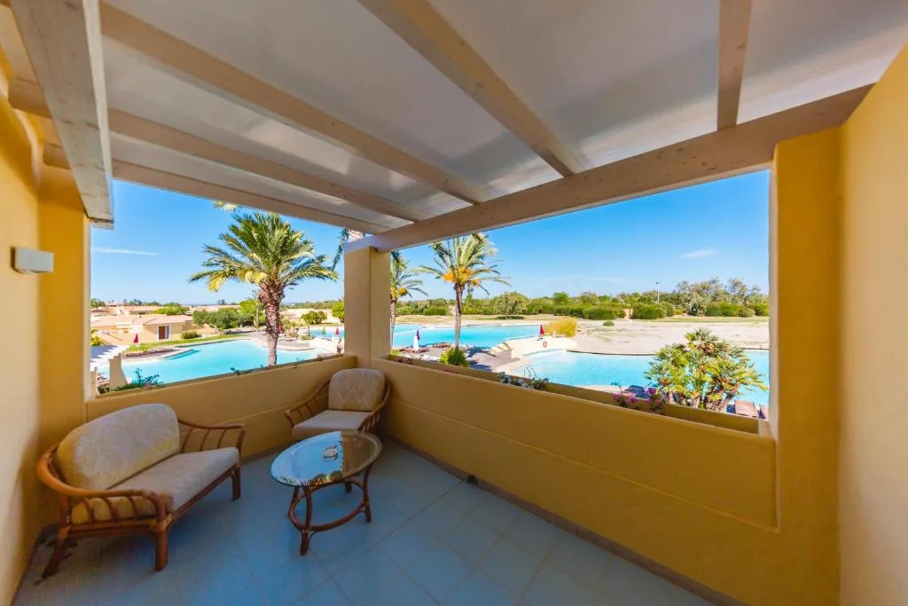 Balcone con poltroncine e vista sulla piscina e le palme del resort