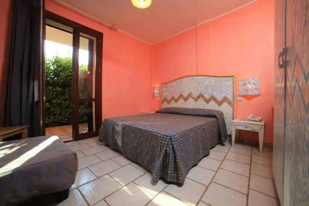 Camera con pareti color corallo, letto matrimoniale e porta finestra che dà sul giardino