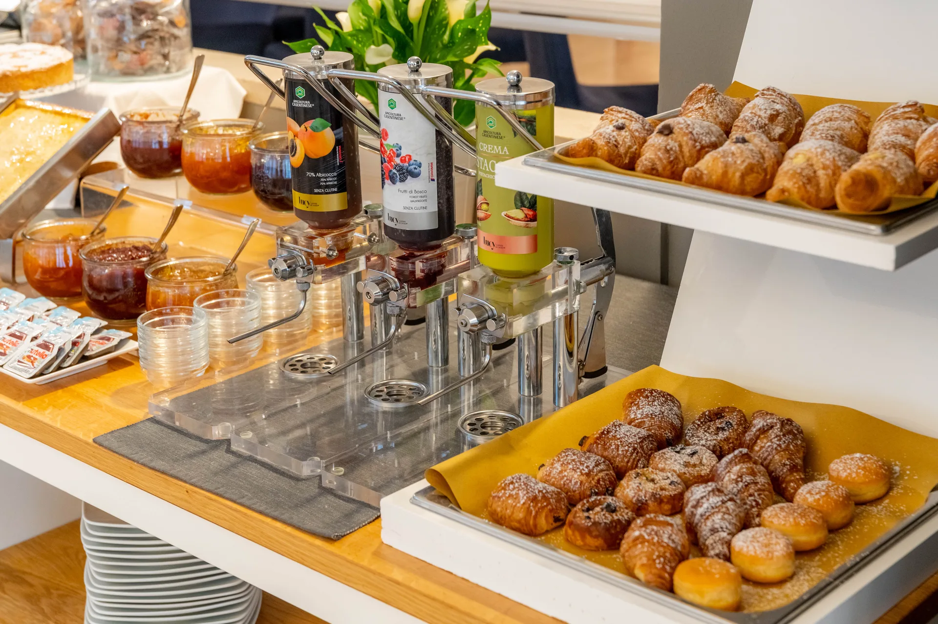 Dettaglio del buffet colazione con dispenser di marmellate e vassoi di cornetti