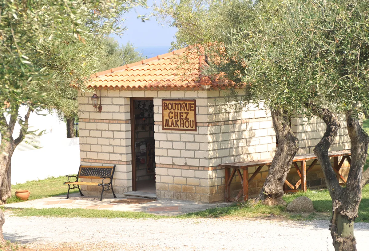 Boutique Chez Makhou in pietra tra gli ulivi con panchina e tavoli all'esterno