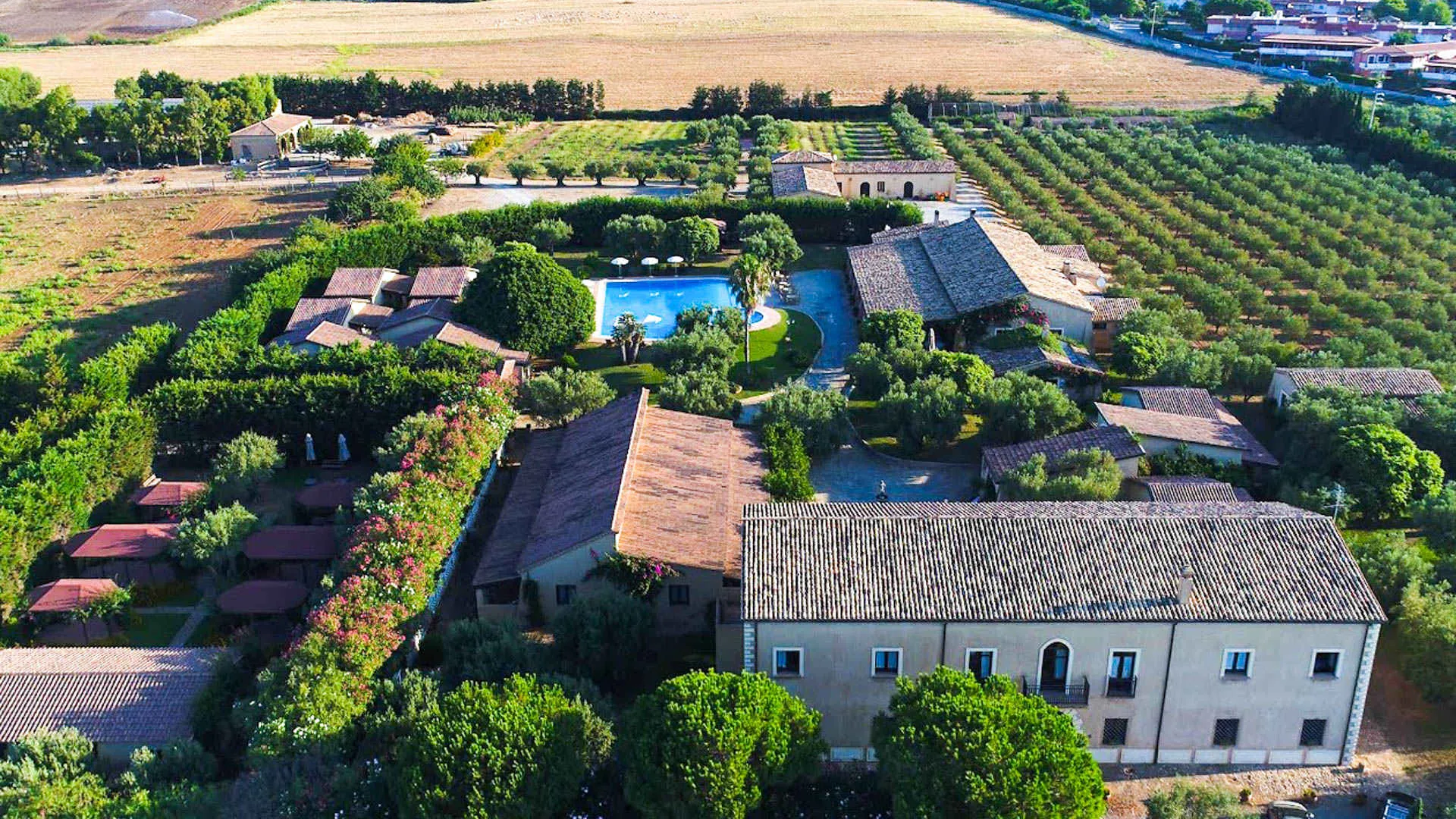 Vista panoramica aerea del resort con edifici in pietra, piscina e campi coltivati