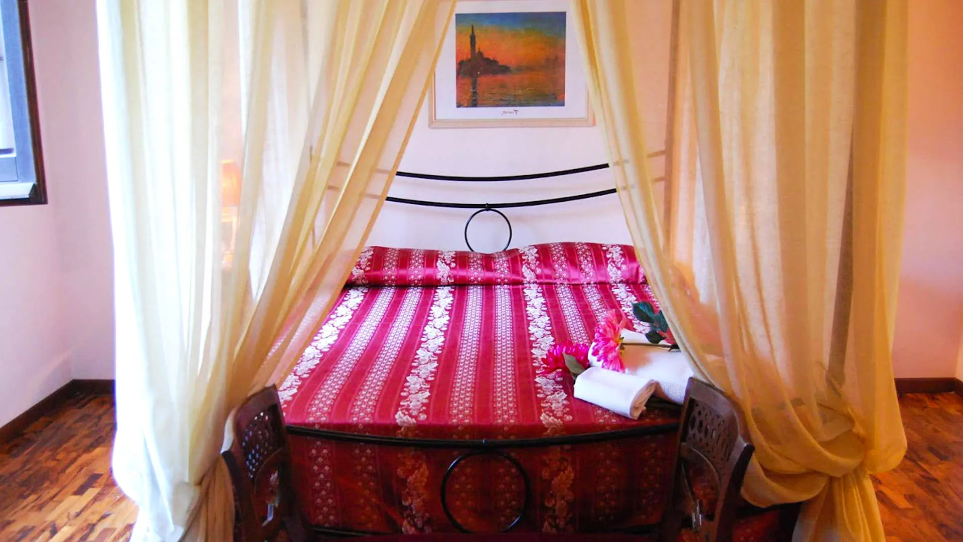 Letto matrimoniale a baldacchino con copriletto rosso e quadro alla parete