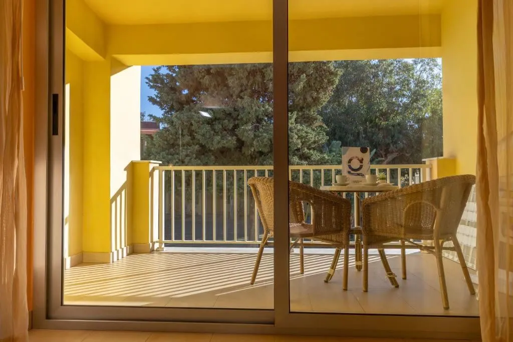 Balcone con tavolino, sedie in vimini e vista sul giardino attraverso porta a vetri