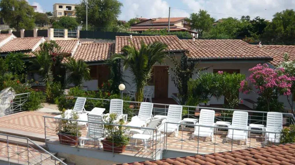 Terrazza esterna con lettini bianchi e camere immerse nel verde