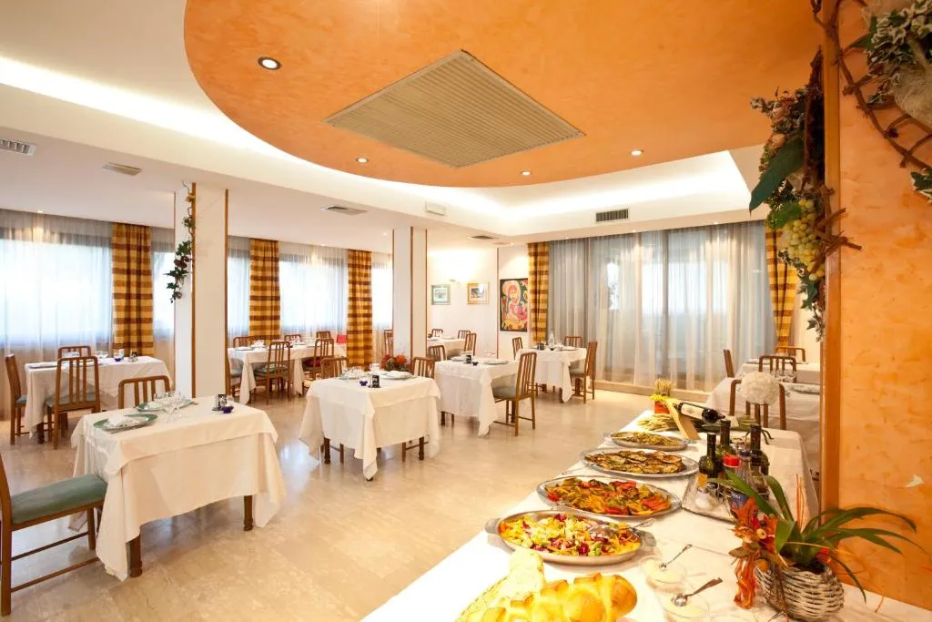 Sala ristorante con tavoli apparecchiati e ricco buffet di piatti