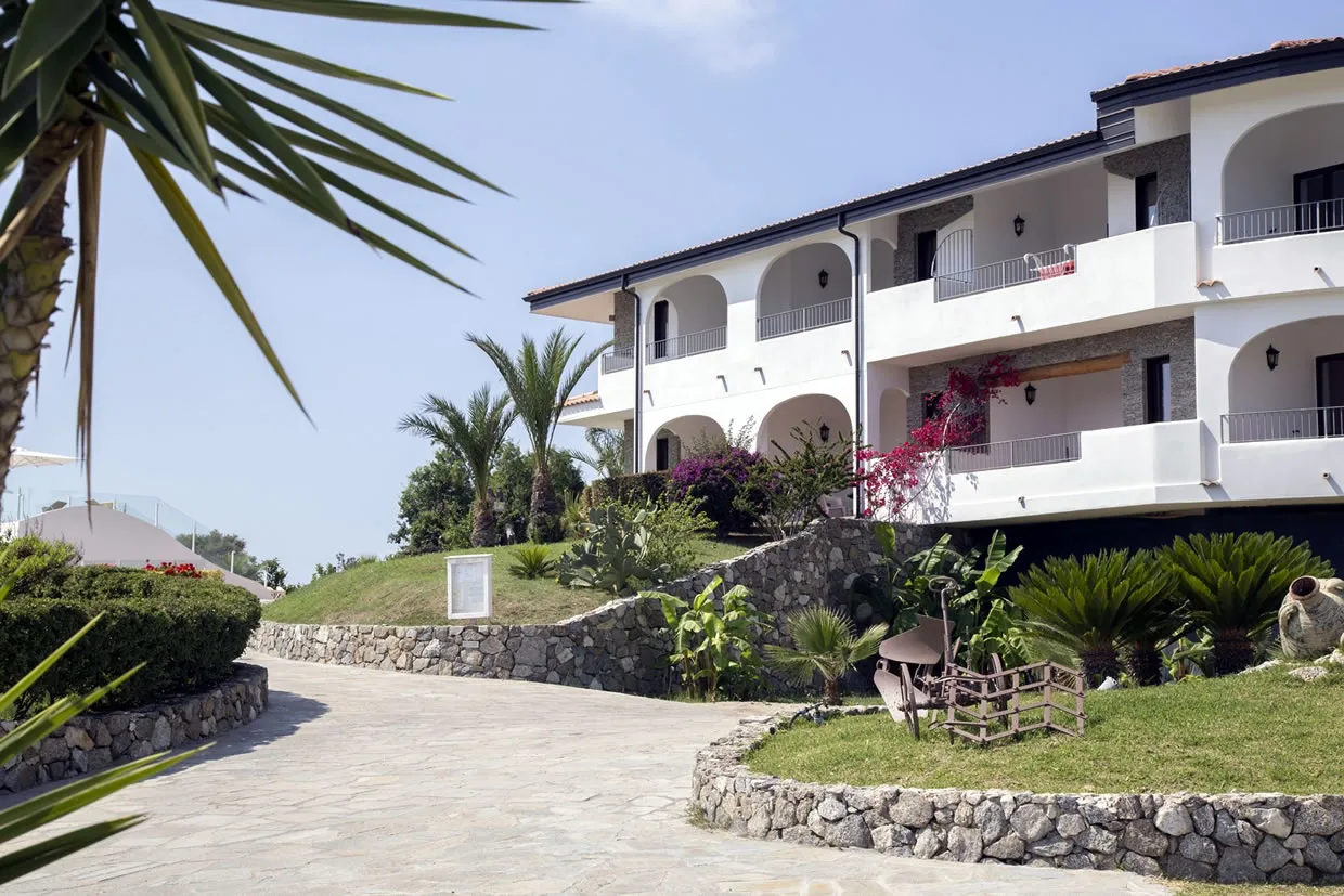 Esterno dell'edificio bianco del resort con archi, balconi e giardini fioriti