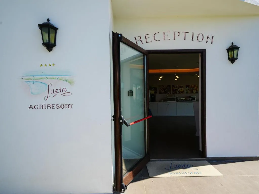 Ingresso reception del Luzia Agriresort con porta aperta e logo dell'hotel