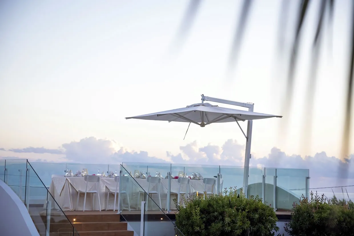 Tavolo apparecchiato sulla terrazza panoramica con ombrellone e vista mare