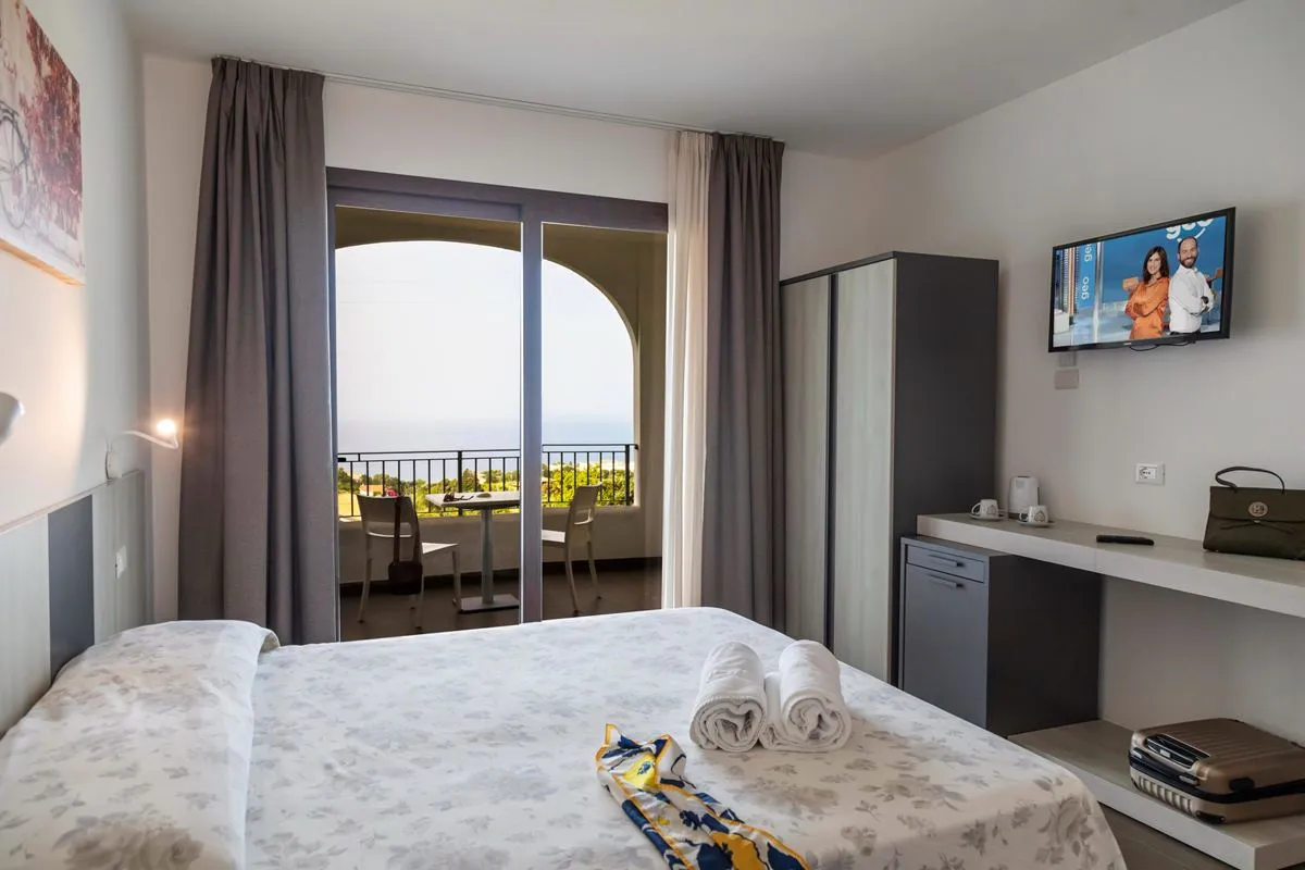 Camera con letto matrimoniale, TV, scrivania e balcone con vista mare