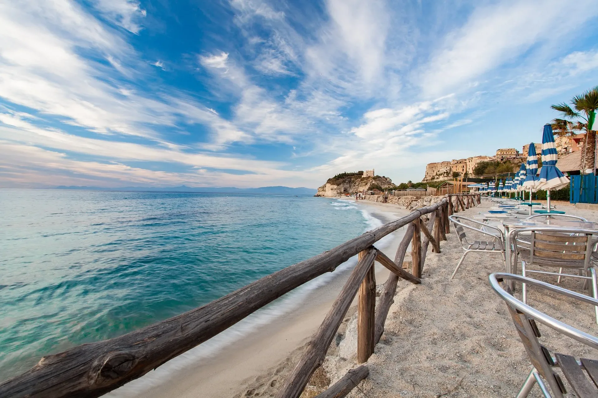 Spiaggia di sabbia con staccionata in legno e vista sul borgo di Tropea