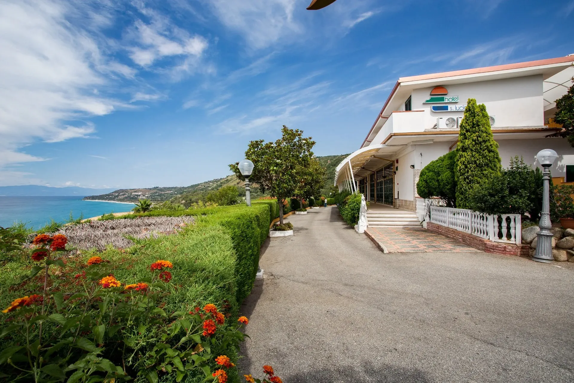 Ingresso dell'hotel Santa Lucia con giardino fiorito e vista sul mare