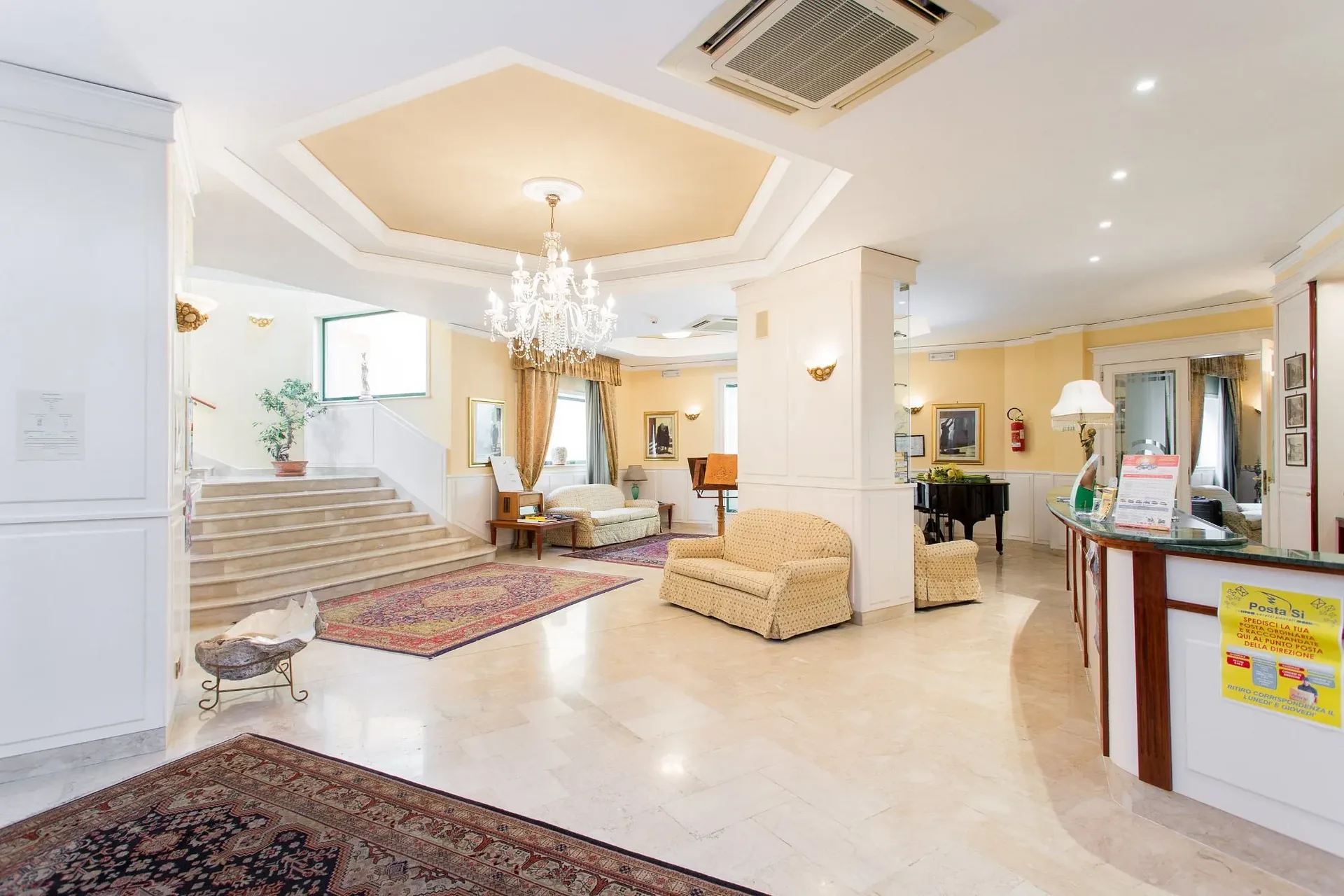 Hall dell'hotel con lampadario di cristallo, reception e scala in marmo