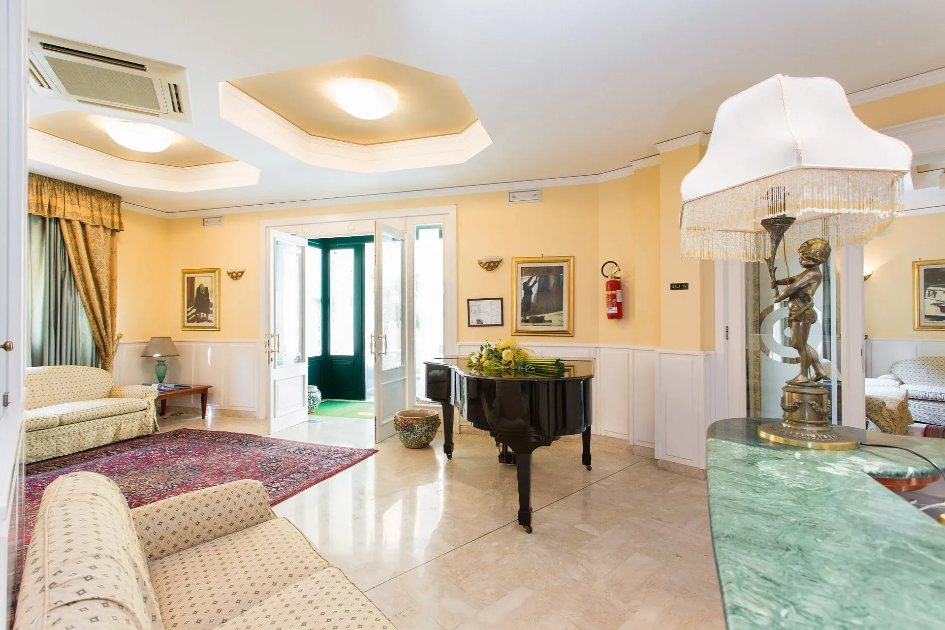 Salone dell'hotel con pianoforte a coda, divani e lampadari