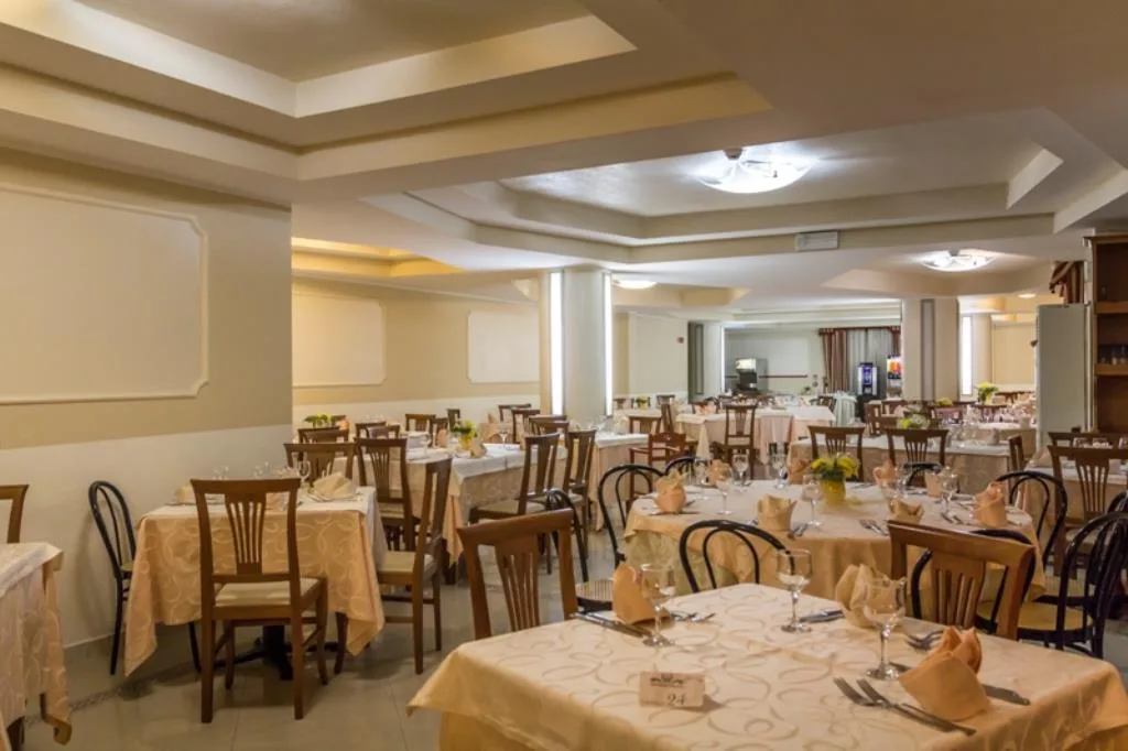 Sala ristorante elegante con tavoli apparecchiati e sedie in legno
