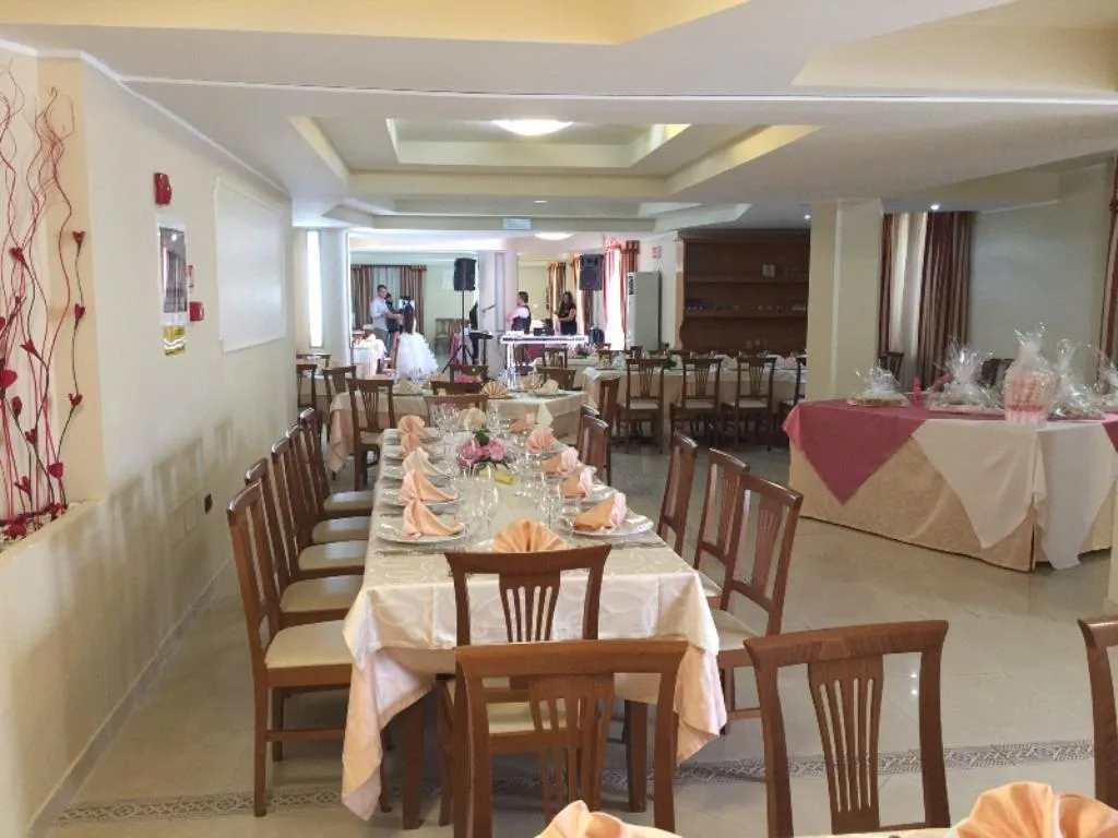 Sala ristorante allestita per evento con tavoli decorati e bomboniere