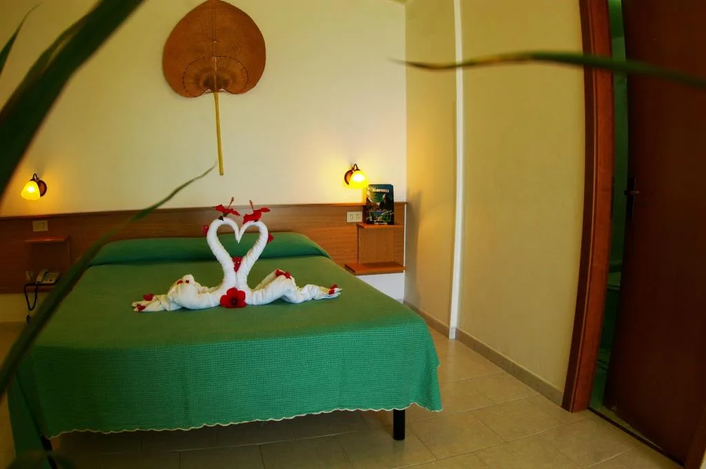 Camera matrimoniale con asciugamani a forma di cigno e fiori sul letto