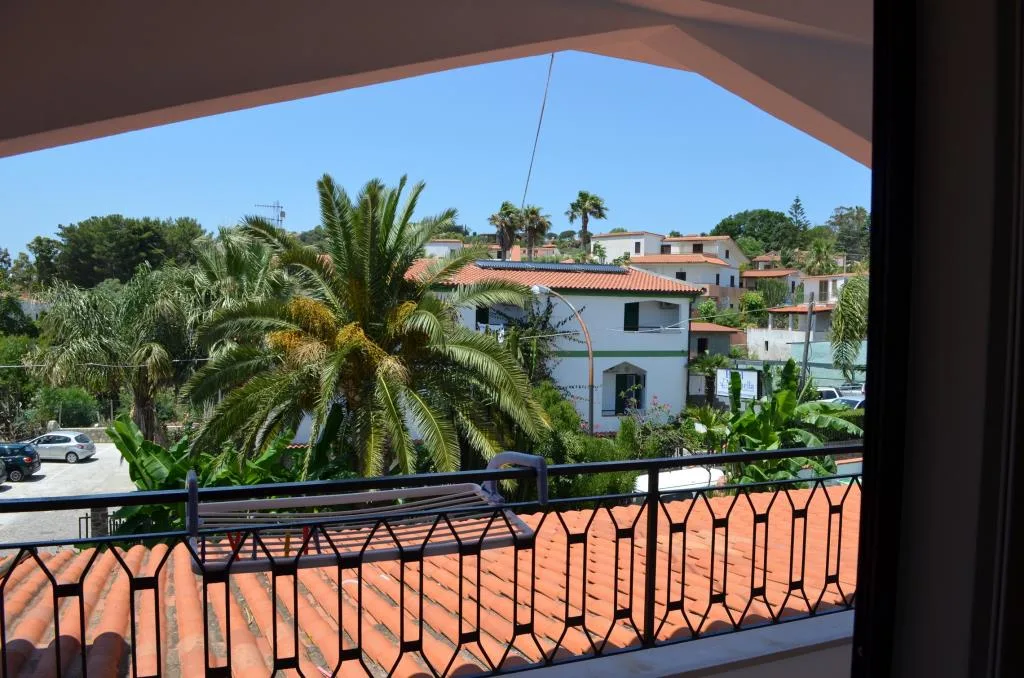 Vista dal balcone su palme, tetti in cotto e abitazioni circostanti