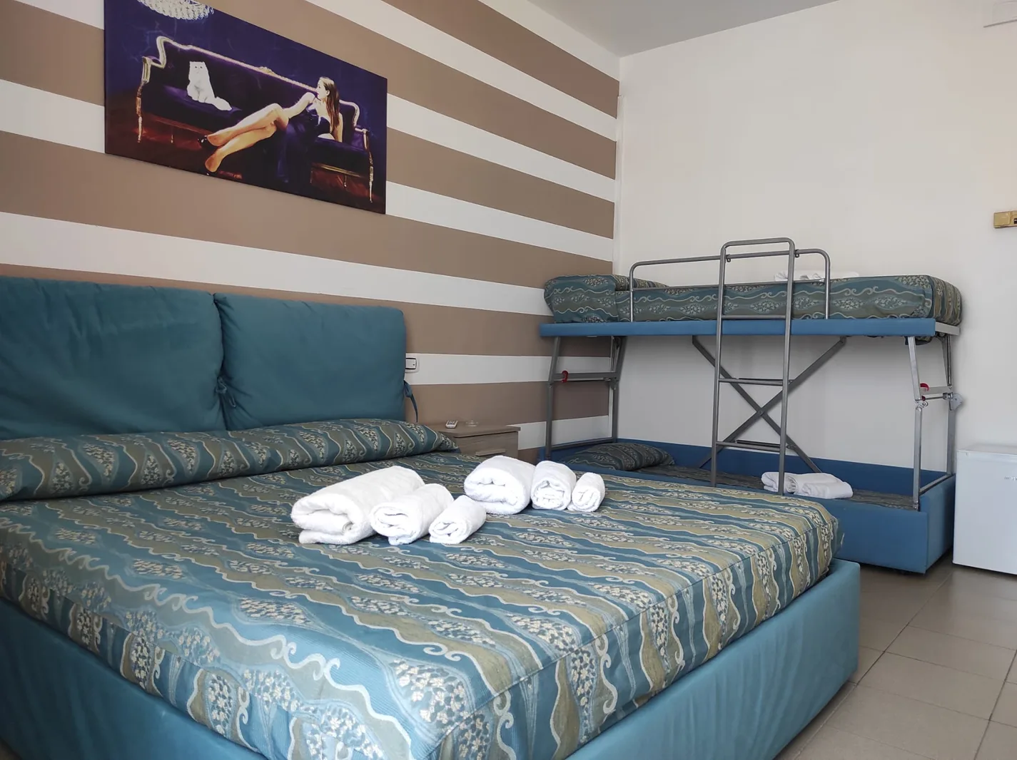 Camera con letto matrimoniale, letto a castello e parete a righe