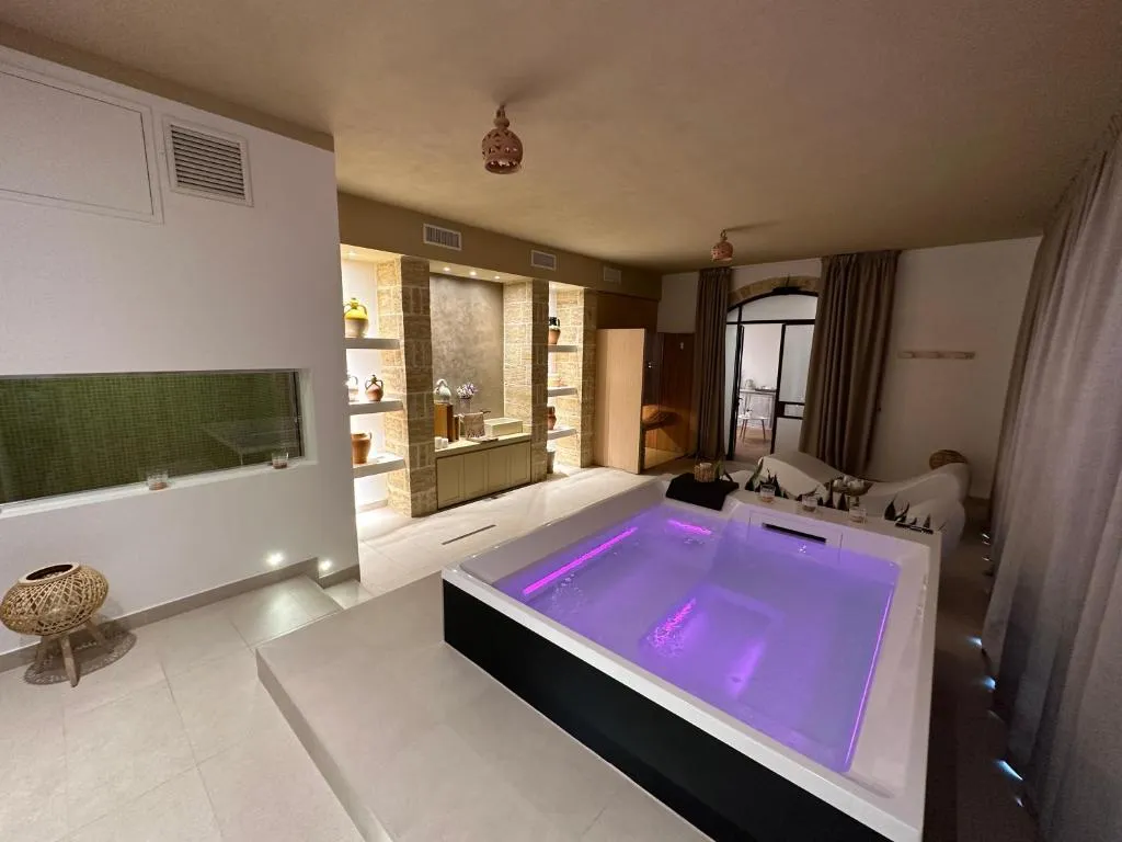 Area spa con vasca idromassaggio illuminata di viola e sauna in legno
