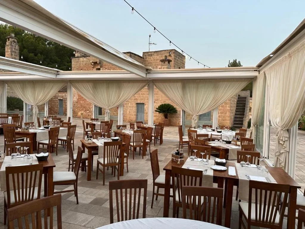 Sala ristorante veranda con tavoli in legno e tende bianche vista sul cortile