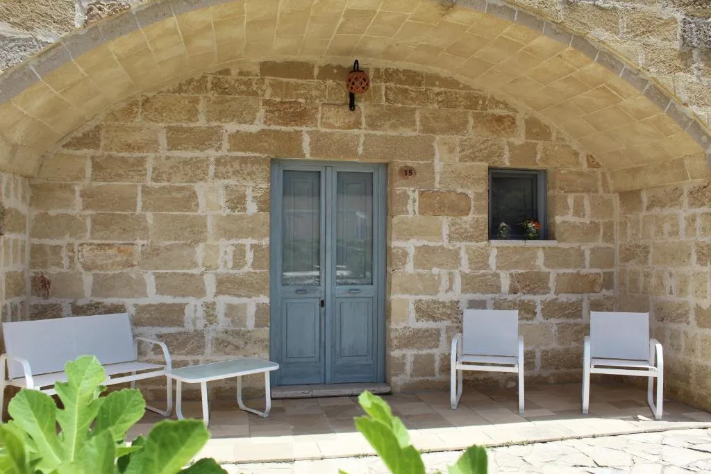 Portico ad arco in pietra con divanetto e poltrone davanti a una porta azzurra
