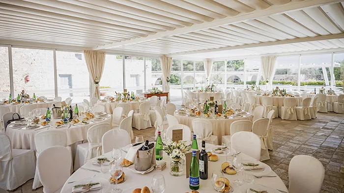 Sala ricevimenti elegante allestita per un evento con tavoli rotondi e tovaglie bianche