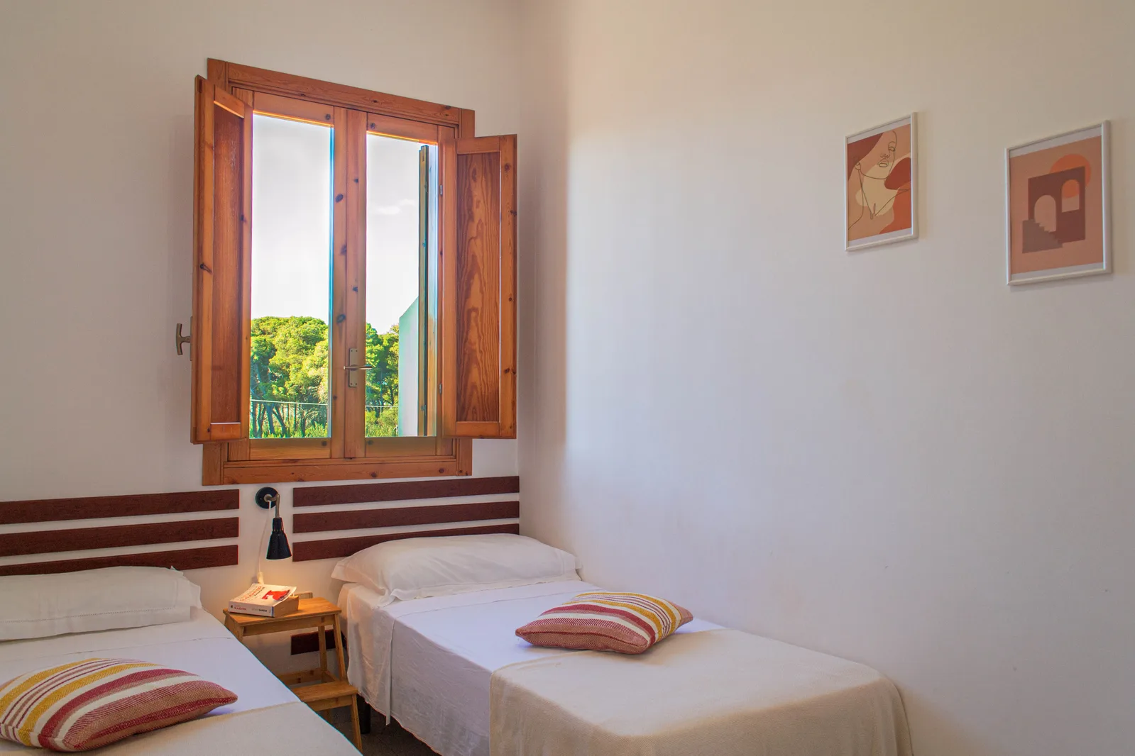 Camera da letto con due letti singoli, finestra in legno con vista sul verde e decorazioni alle pareti