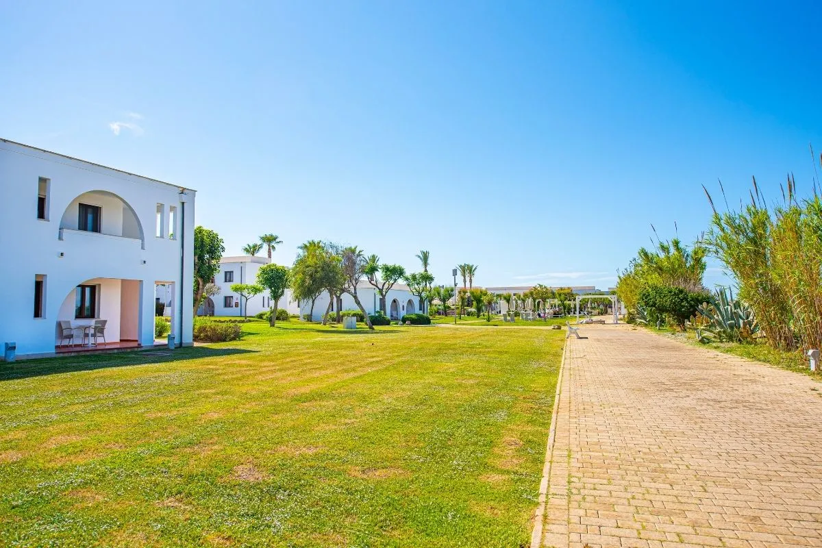 Ampio prato verde del resort con edifici bianchi, palme e vialetto