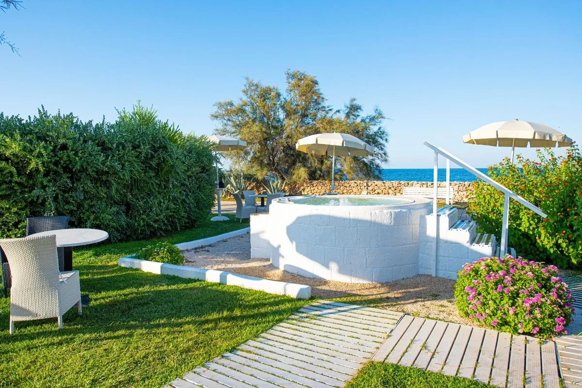 Vasca idromassaggio esterna con ombrelloni nel giardino vista mare