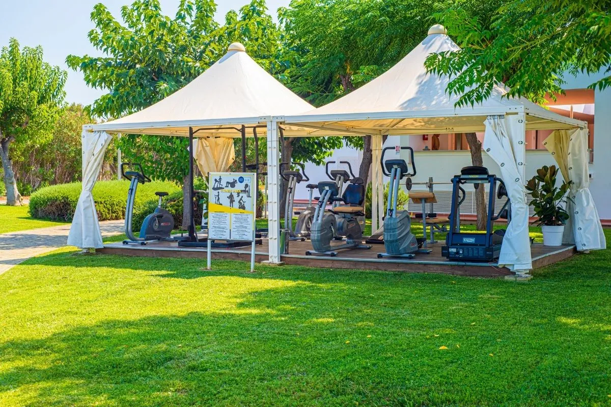 Palestra all'aperto sotto gazebo bianchi con attrezzi fitness nel giardino