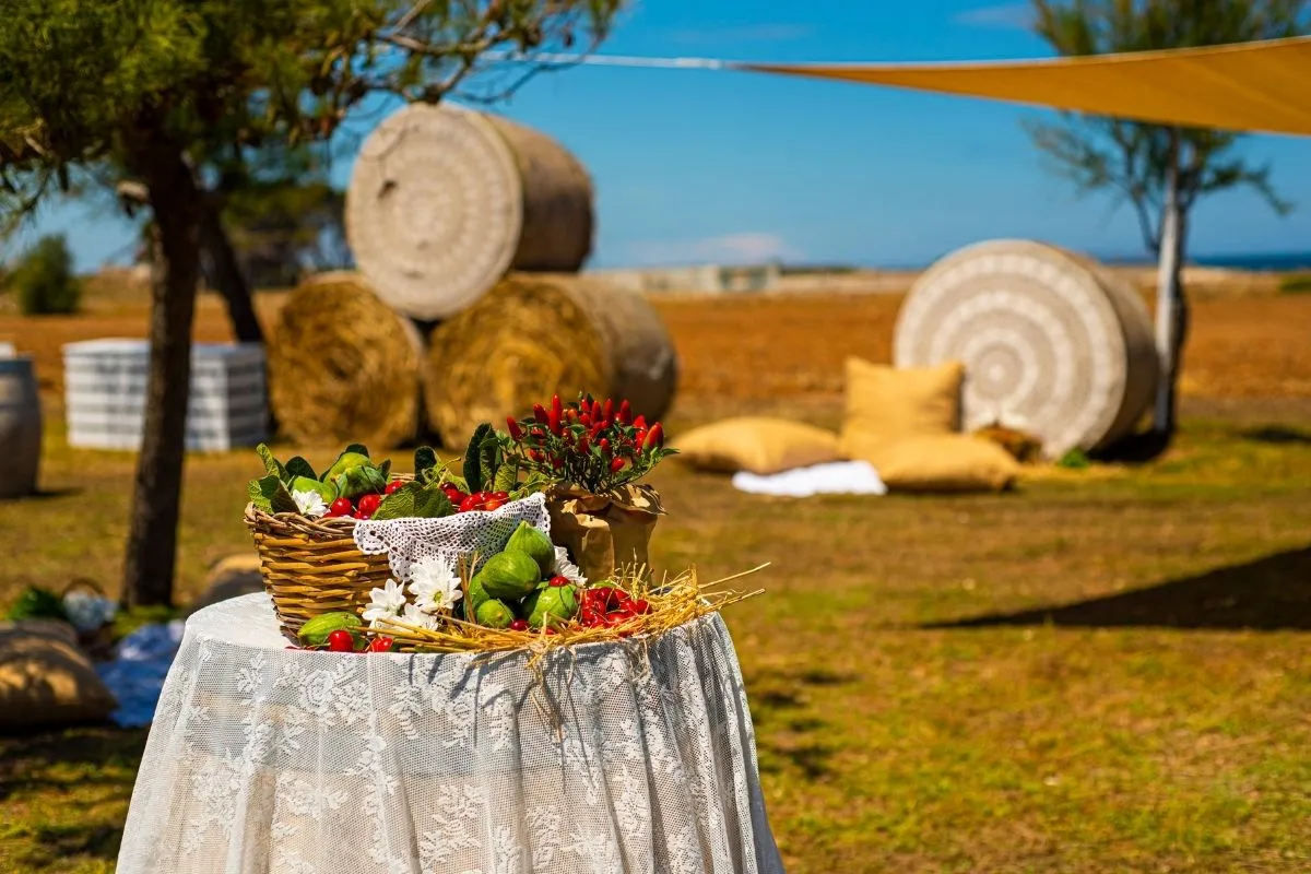 Allestimento campestre con cesto di prodotti tipici e balle di fieno
