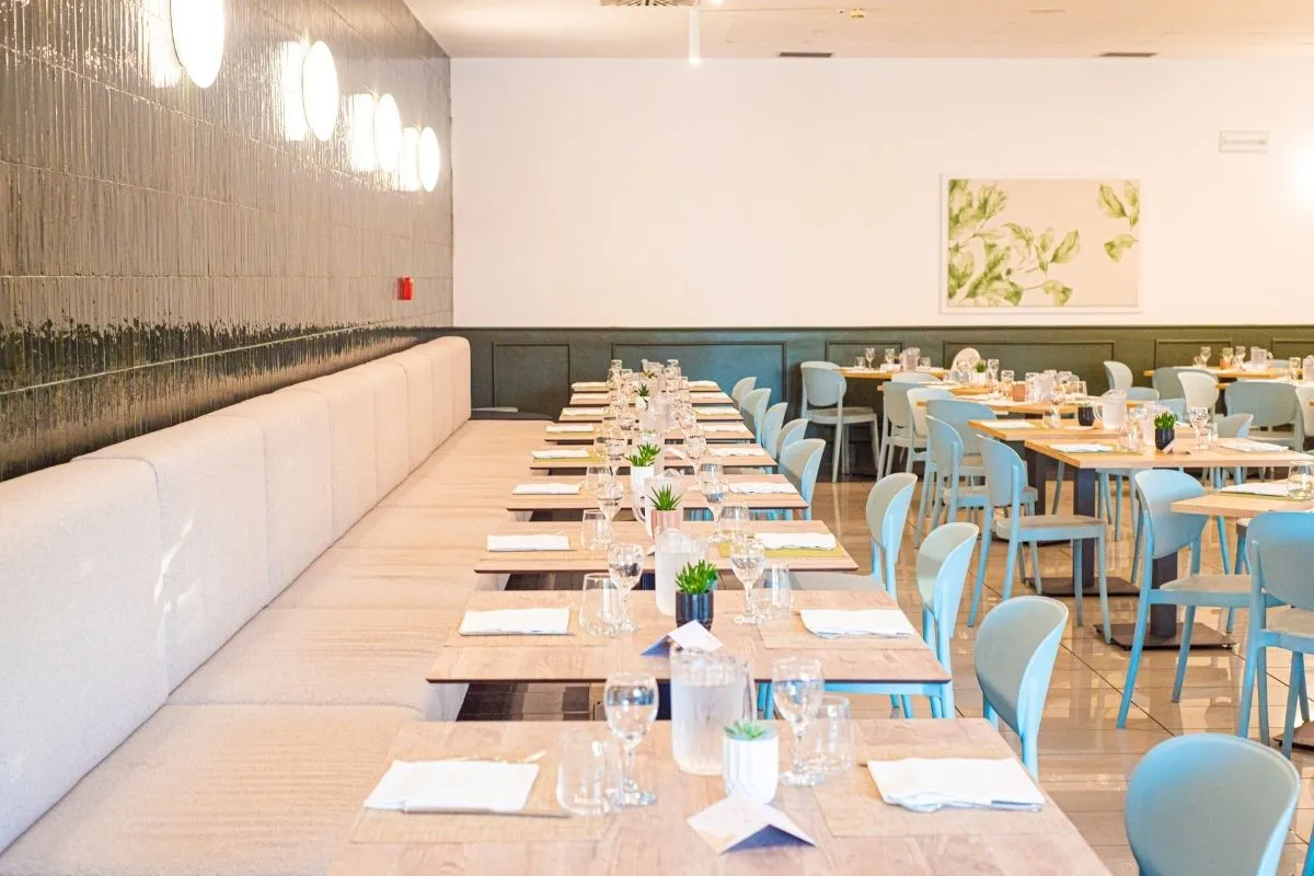 Sala ristorante interna con tavoli in legno, sedute azzurre e divano