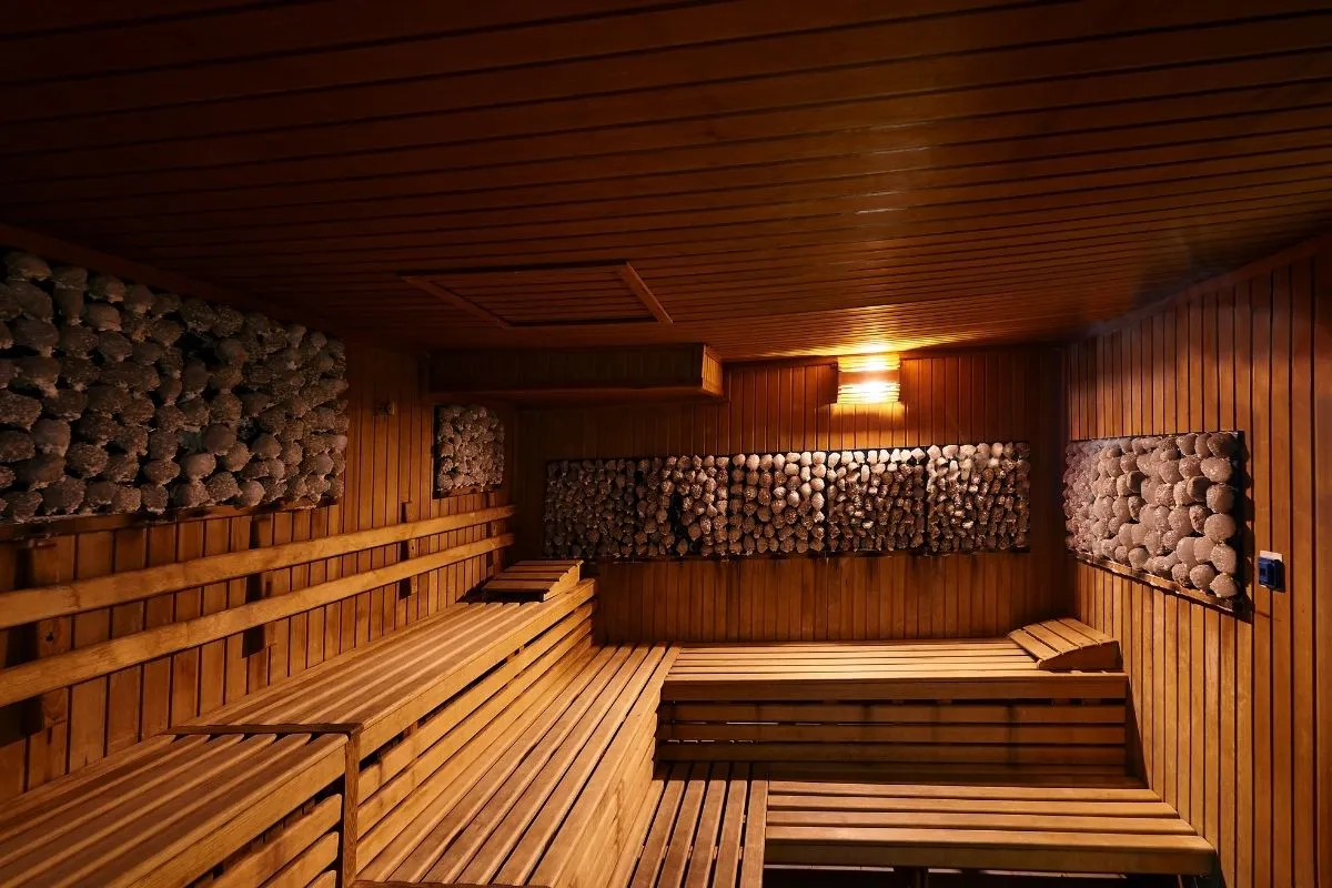 Sauna finlandese in legno con pareti rivestite di pietre
