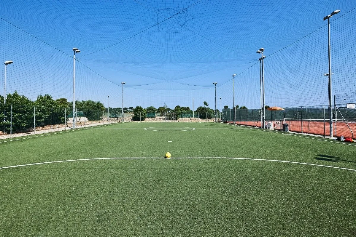Campo da calcetto in erba sintetica con rete e cielo azzurro