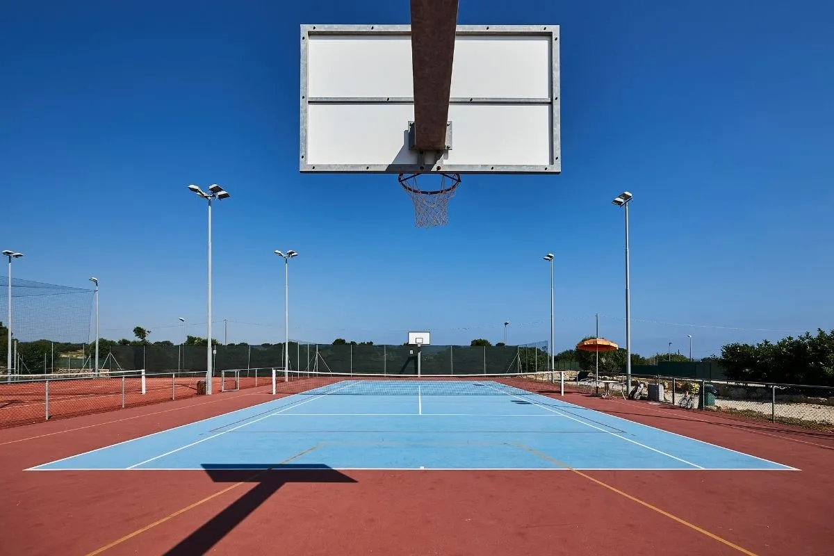 Campo da basket e tennis all'aperto con canestro sotto cielo azzurro