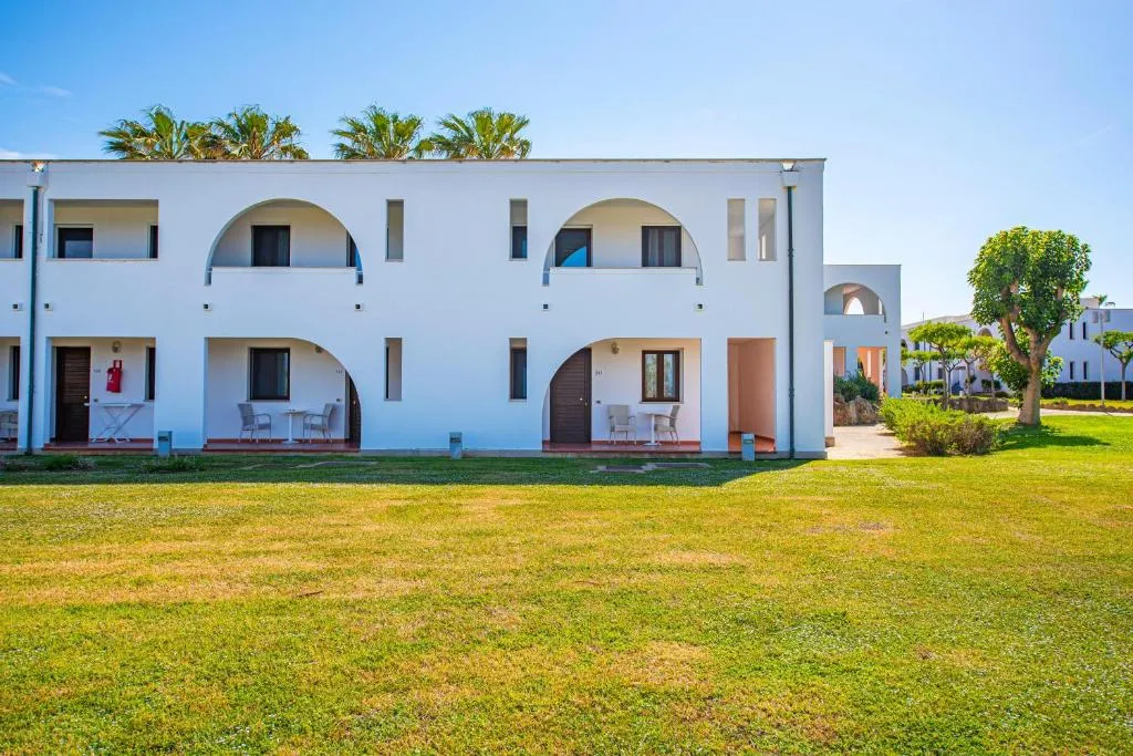 Edificio bianco del resort con archi, terrazze e prato verde