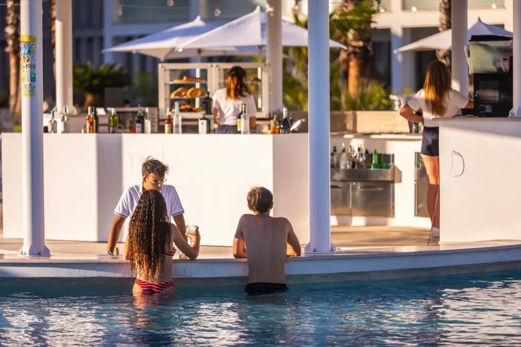 Ospiti al pool bar con barista che serve drink al tramonto