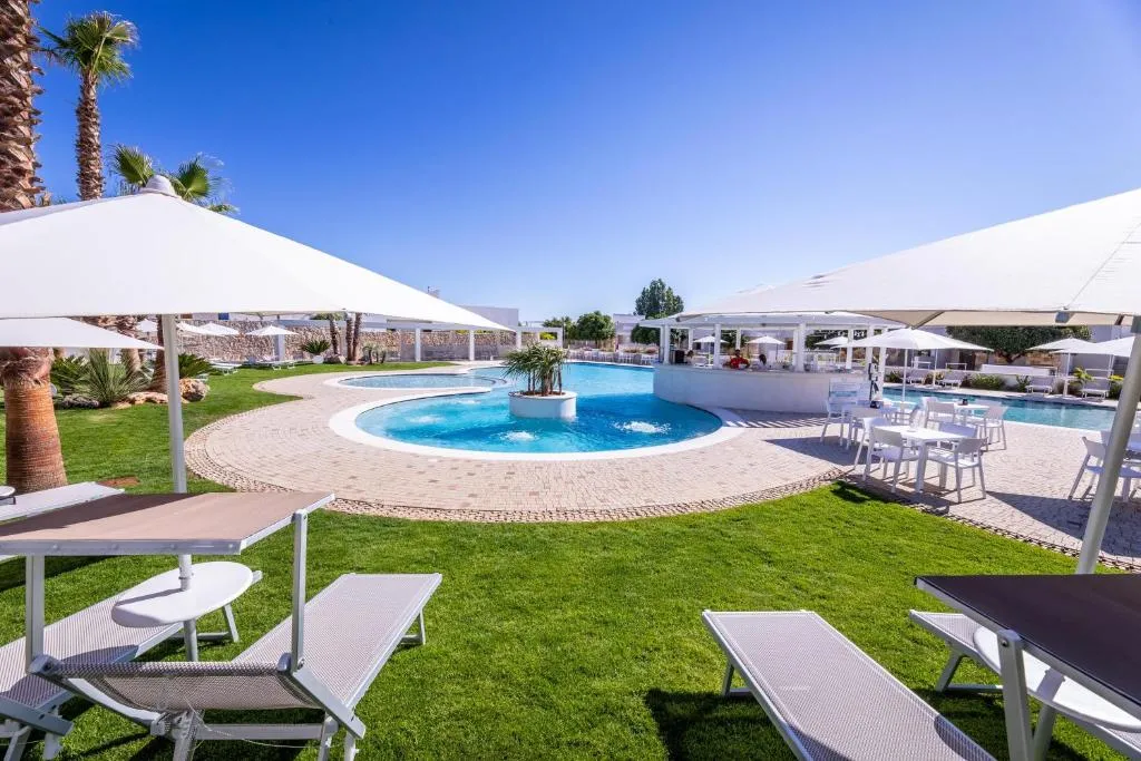 Giardino con lettini e ombrelloni bianchi affacciati sulla piscina