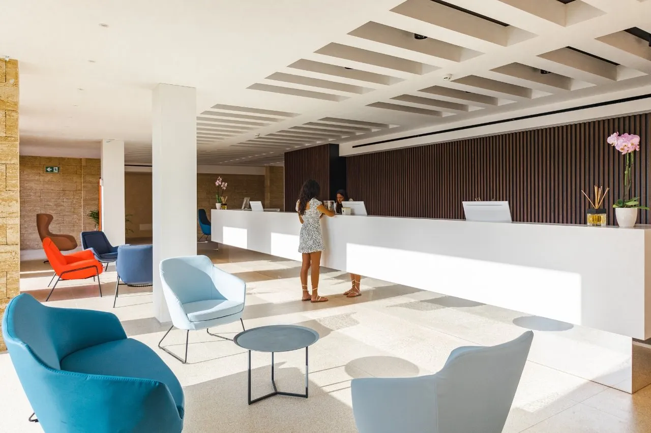 Hall moderna con reception bianca e poltrone colorate
