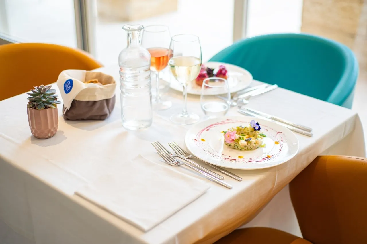 Tavolo del ristorante apparecchiato con piatto gourmet e vino