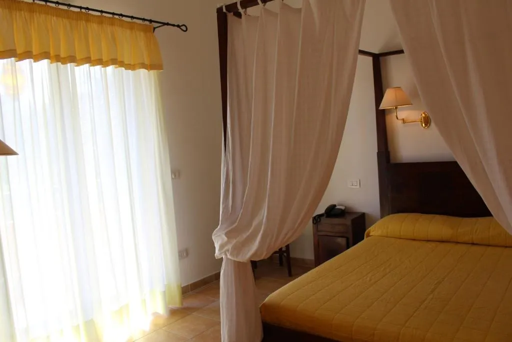 Camera con letto a baldacchino e tende bianche vicino alla finestra